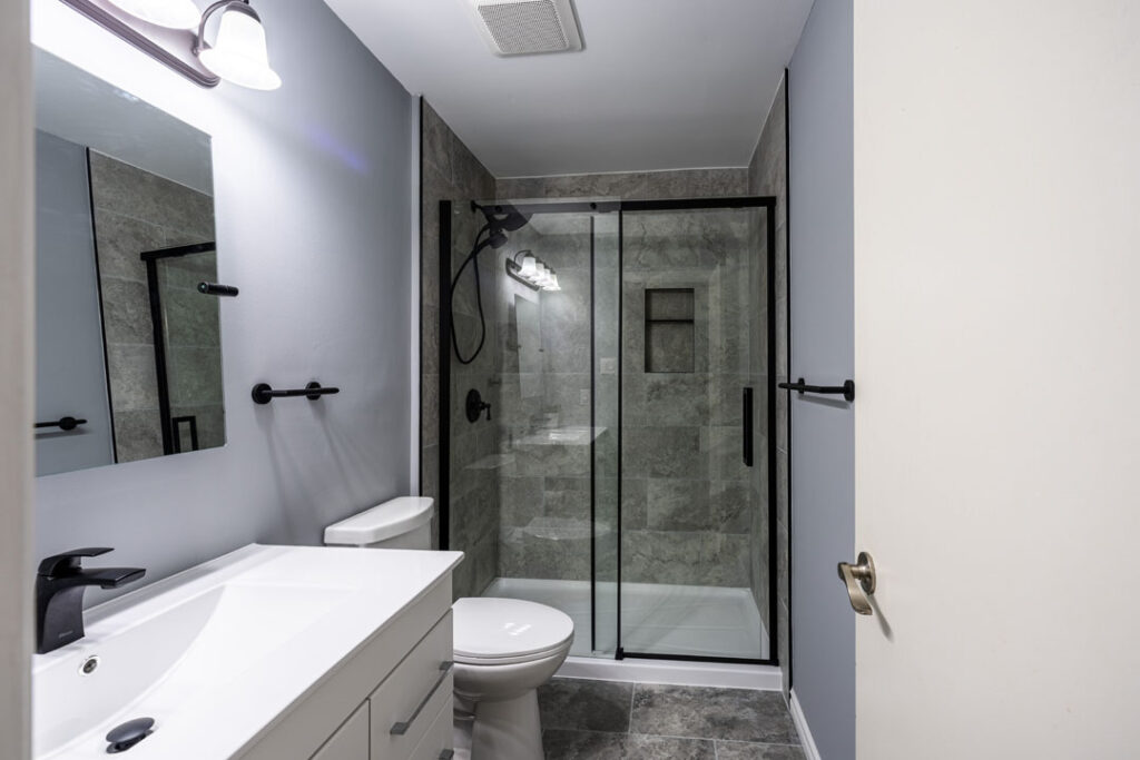 renovated bathroom with marble tiles and flooring with vanity and toilet
