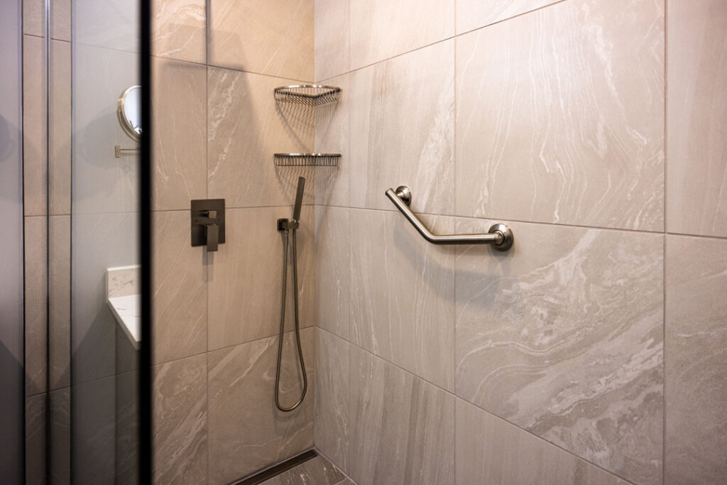 large marble tiled shower wall with attached grab on handle