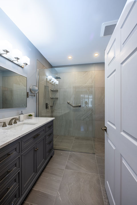 single vanity sink with the walk in shower and tile flooring