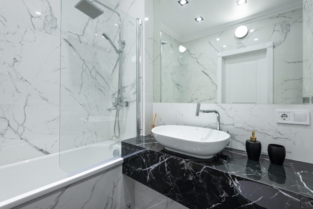 black marble vanity with vessel countertop and big mirror with bathtub