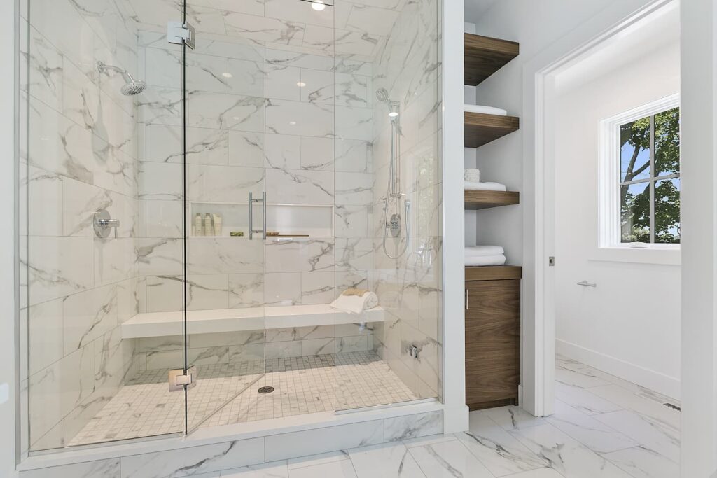 customized storage shelfs with marble tiled shower wall and sitting bench inside