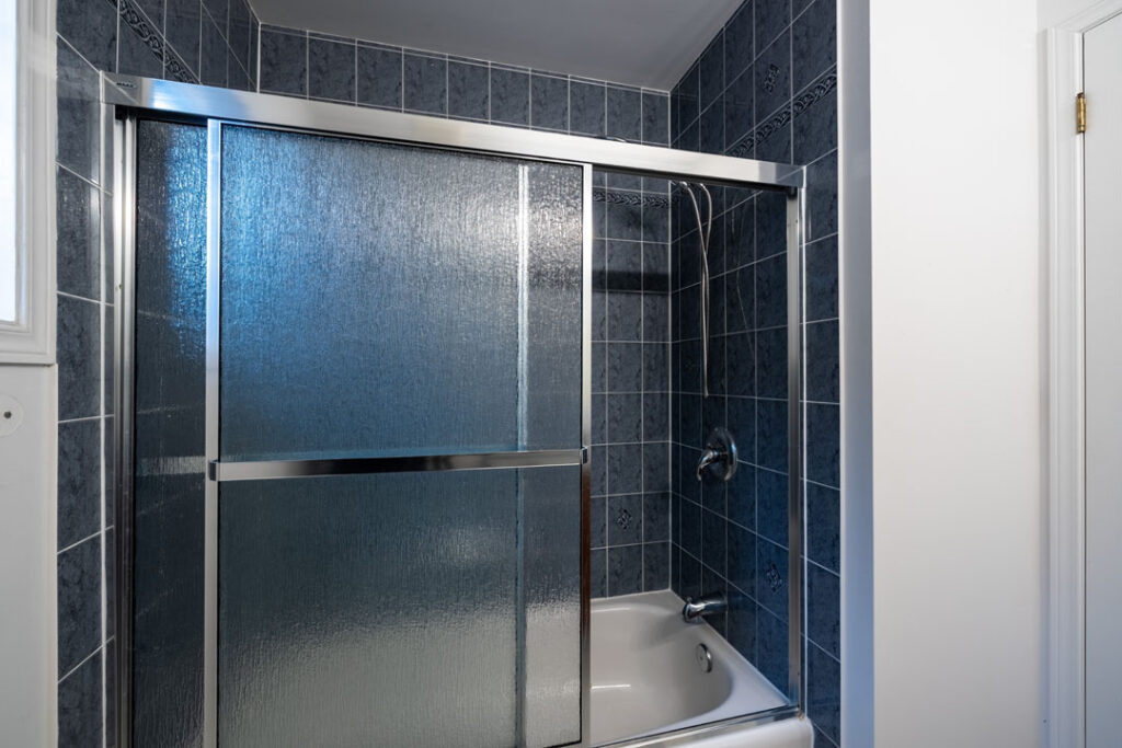 bath tub shower room with blurred glass sliding door