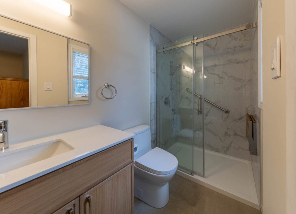 Accessible shower with marble-look wall tile and porcelain bathroom flooring in Barrhaven
