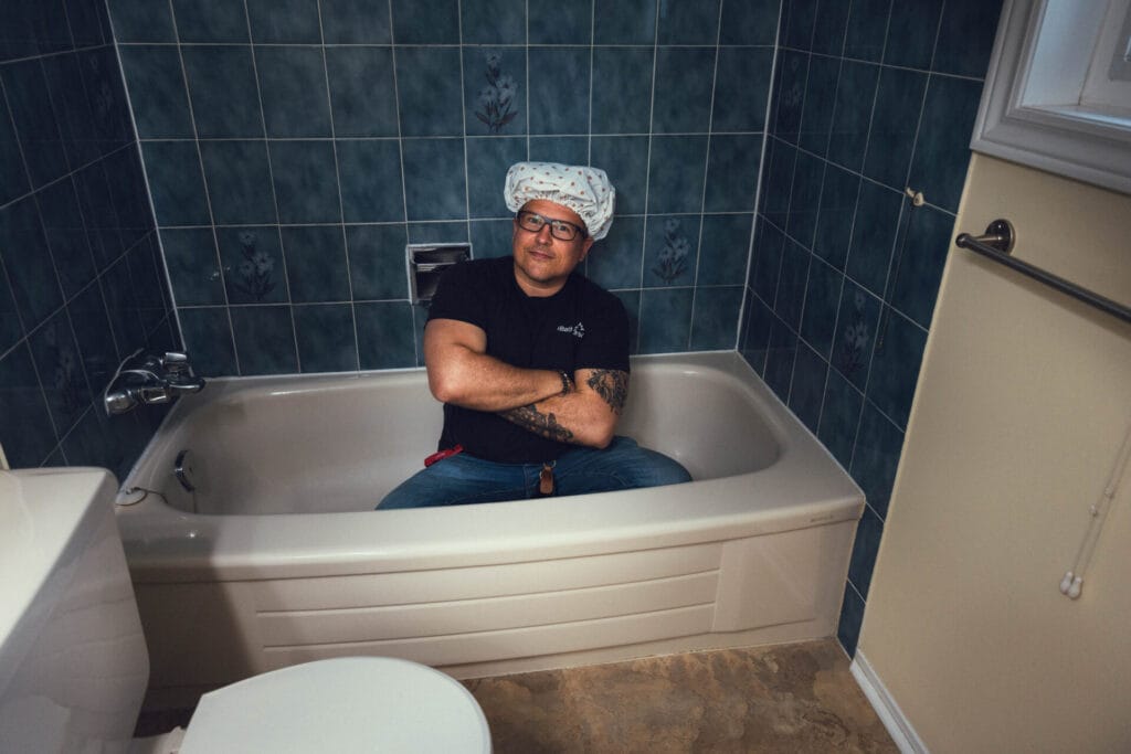 iBathrooms contractor Yuri joking in bathtub before bathroom demolition